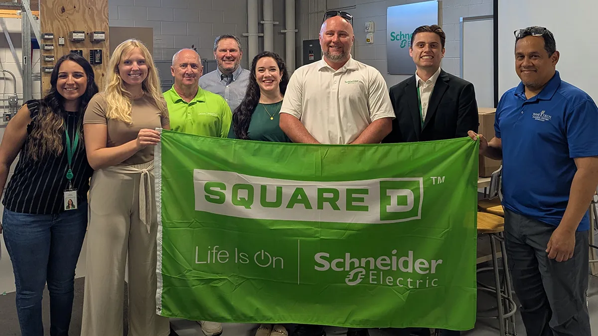 Schneider Electric staff pose for a photo behind a company banner.