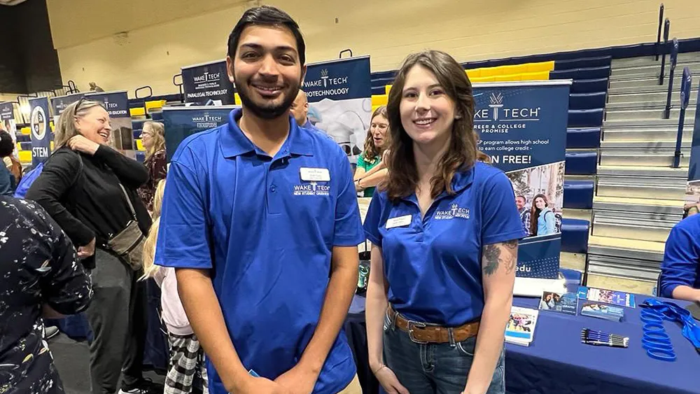 Two Wake Tech representatives standing in front of an information table. 