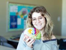 A Neurodiagnostic Technology student poses with a model of a brain.