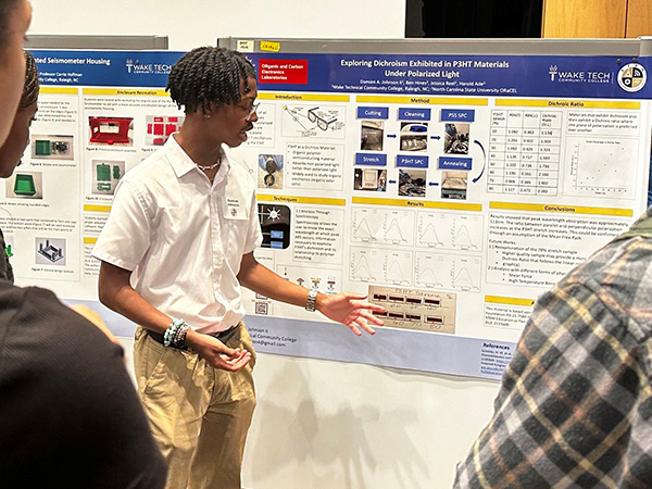 A student shows off his poster outlining his undergraduate research project at Wake Tech.