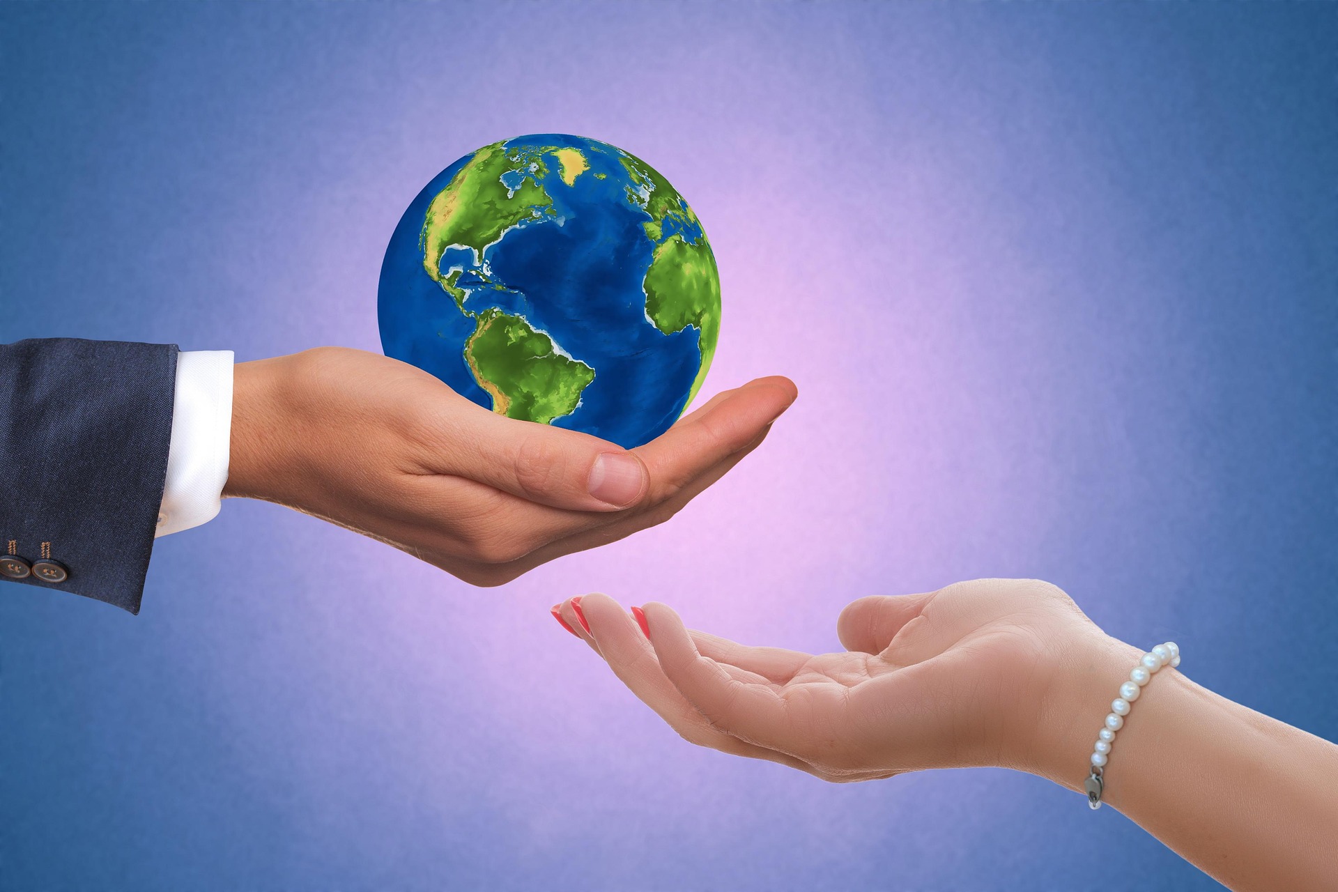 Hand holding a globe with another hand nearby