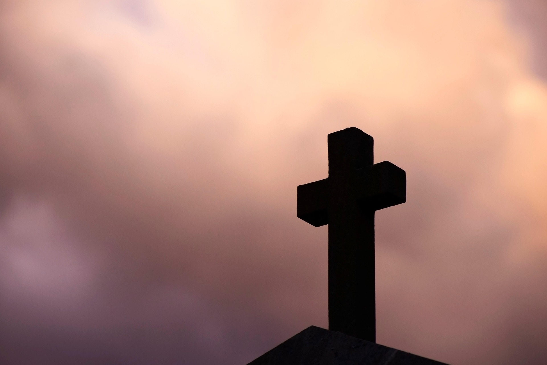 Silhouette of a cross against a cloudy sky