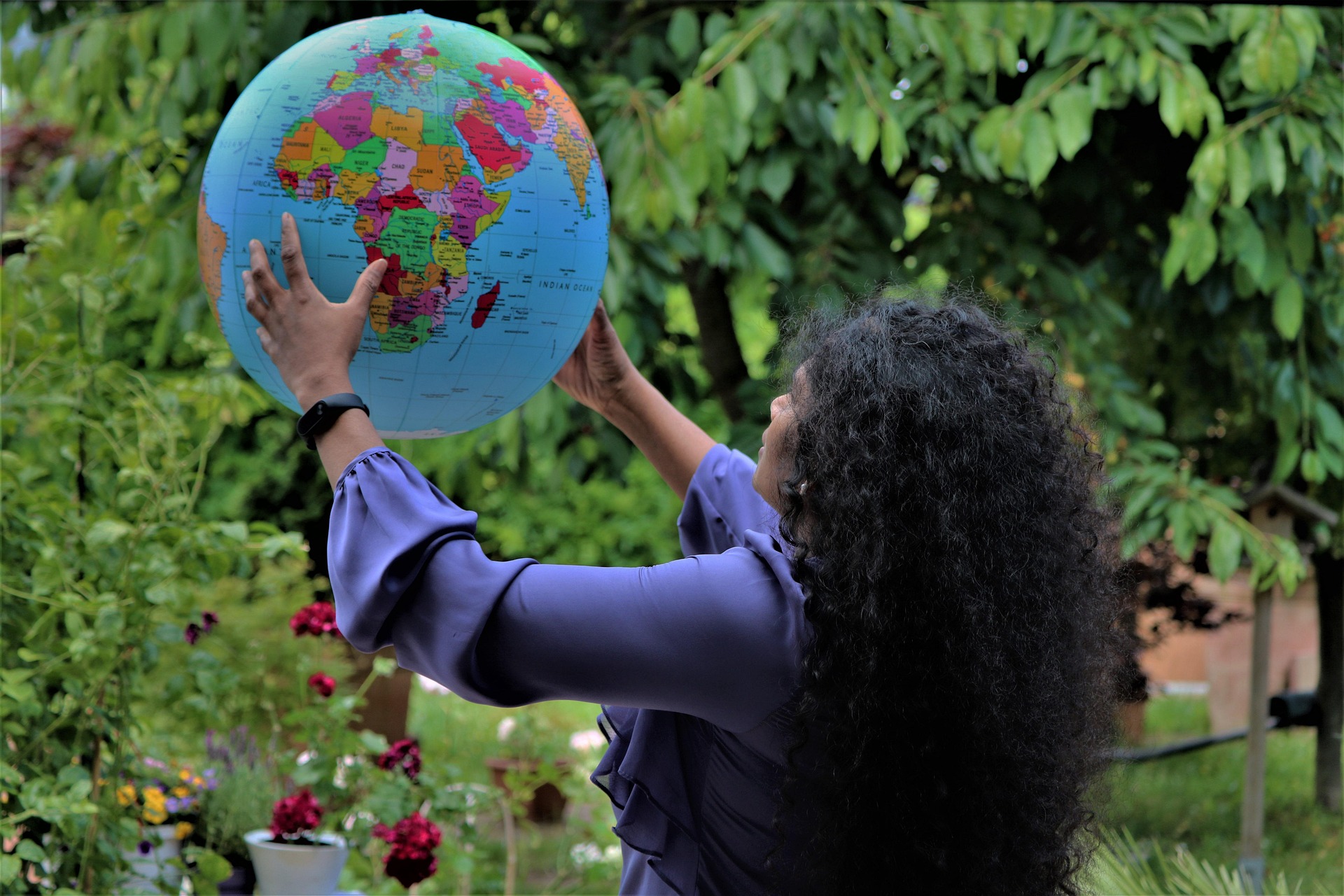 A woman standing in a garden holding a globe