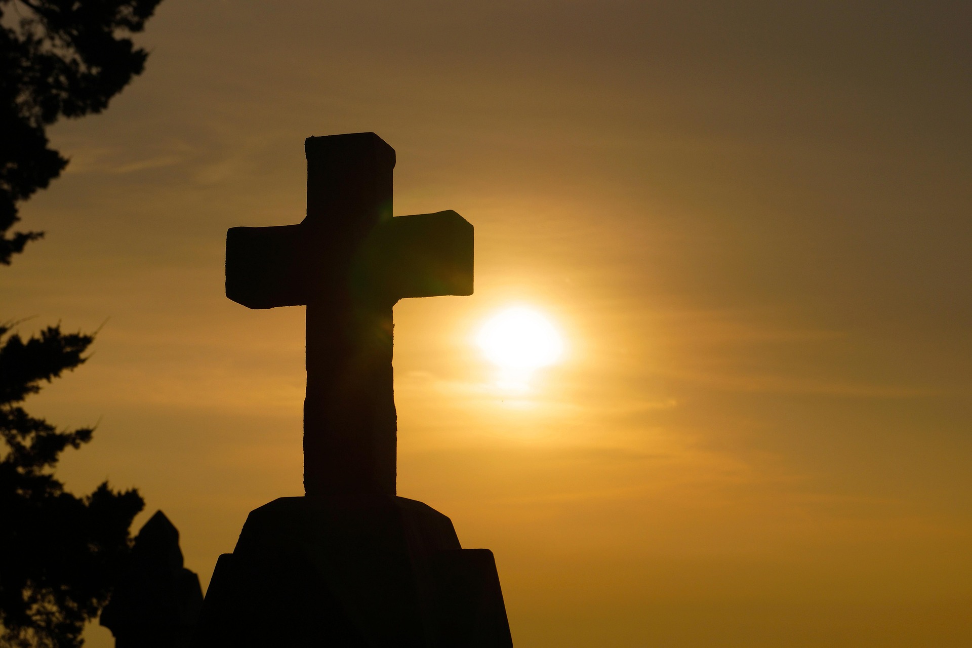 Silhouette of a cross against a sunrise