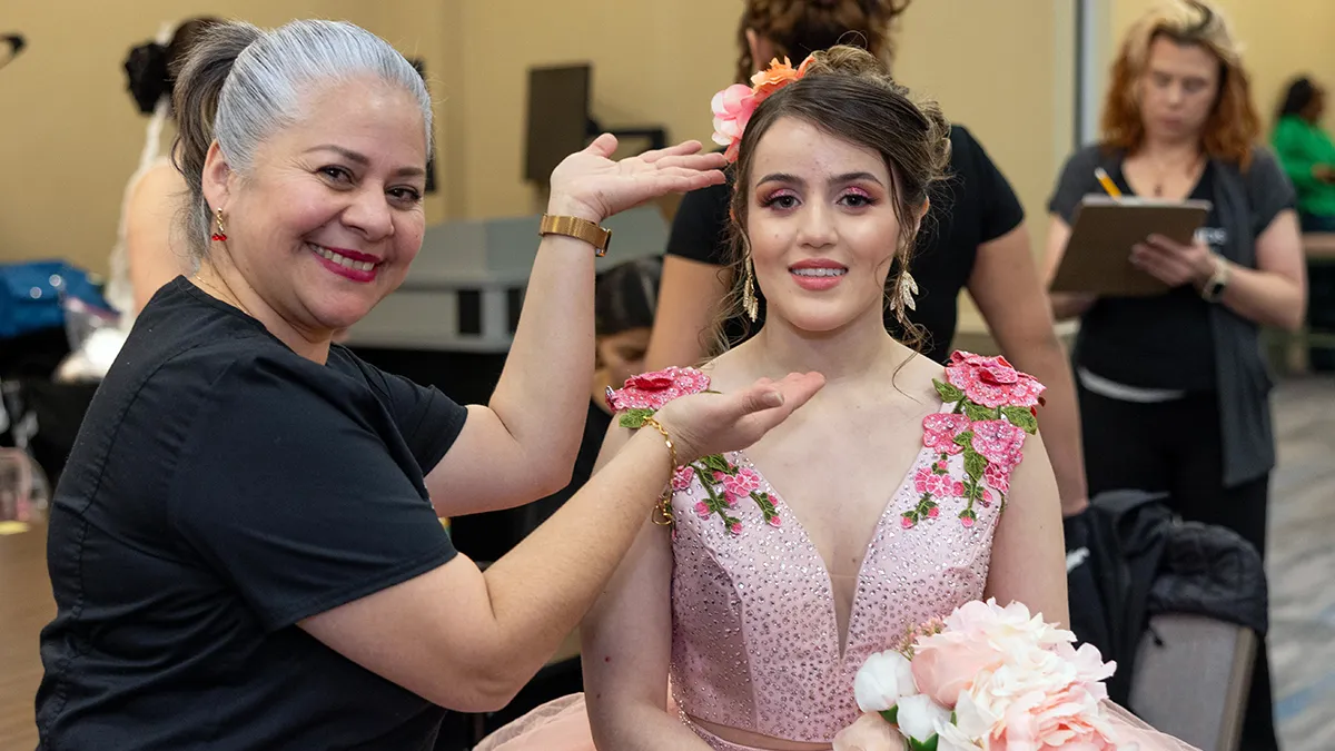 A Cosmetology student shows off her work on another student.