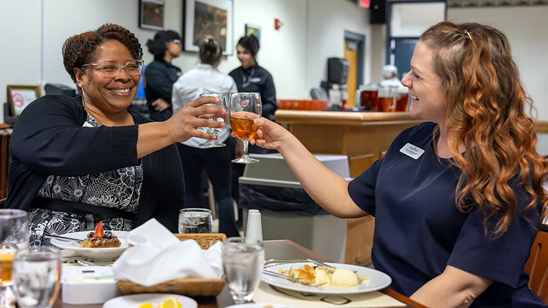 Two women share a toast during the Career Services Dining Etiquette Luncheon.