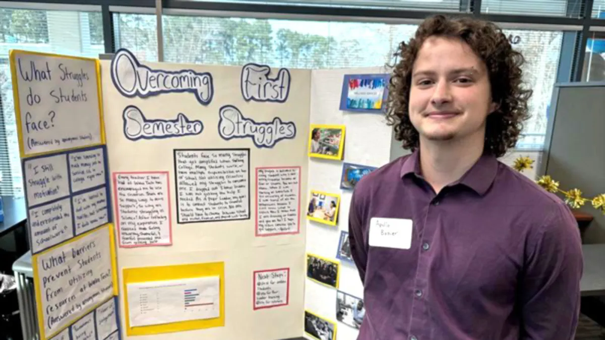 A Wake Tech student stands next to a poster of a project he completed as a Peer Leader.