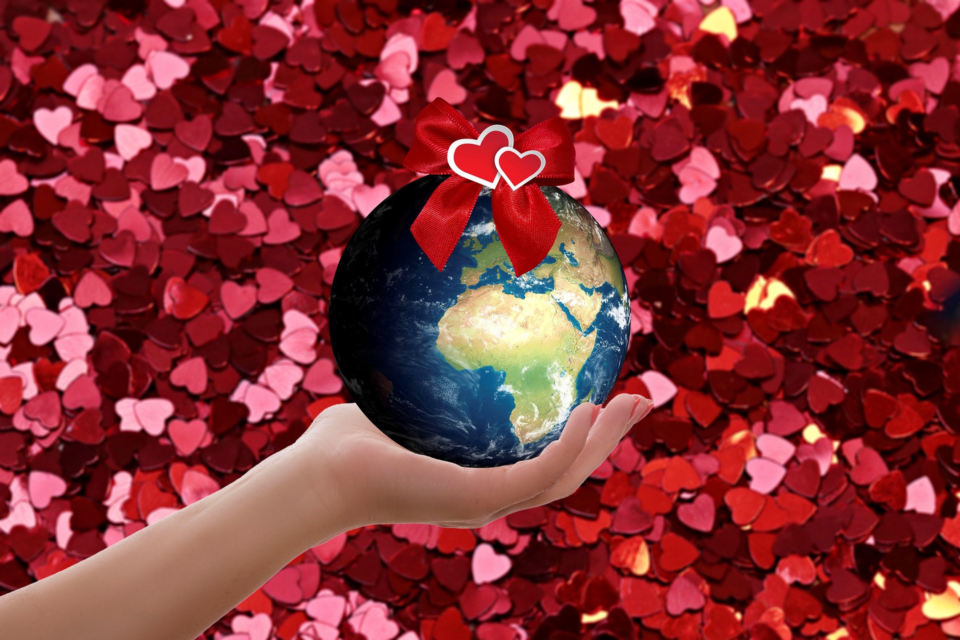 Hand holding a globe with hearts on it