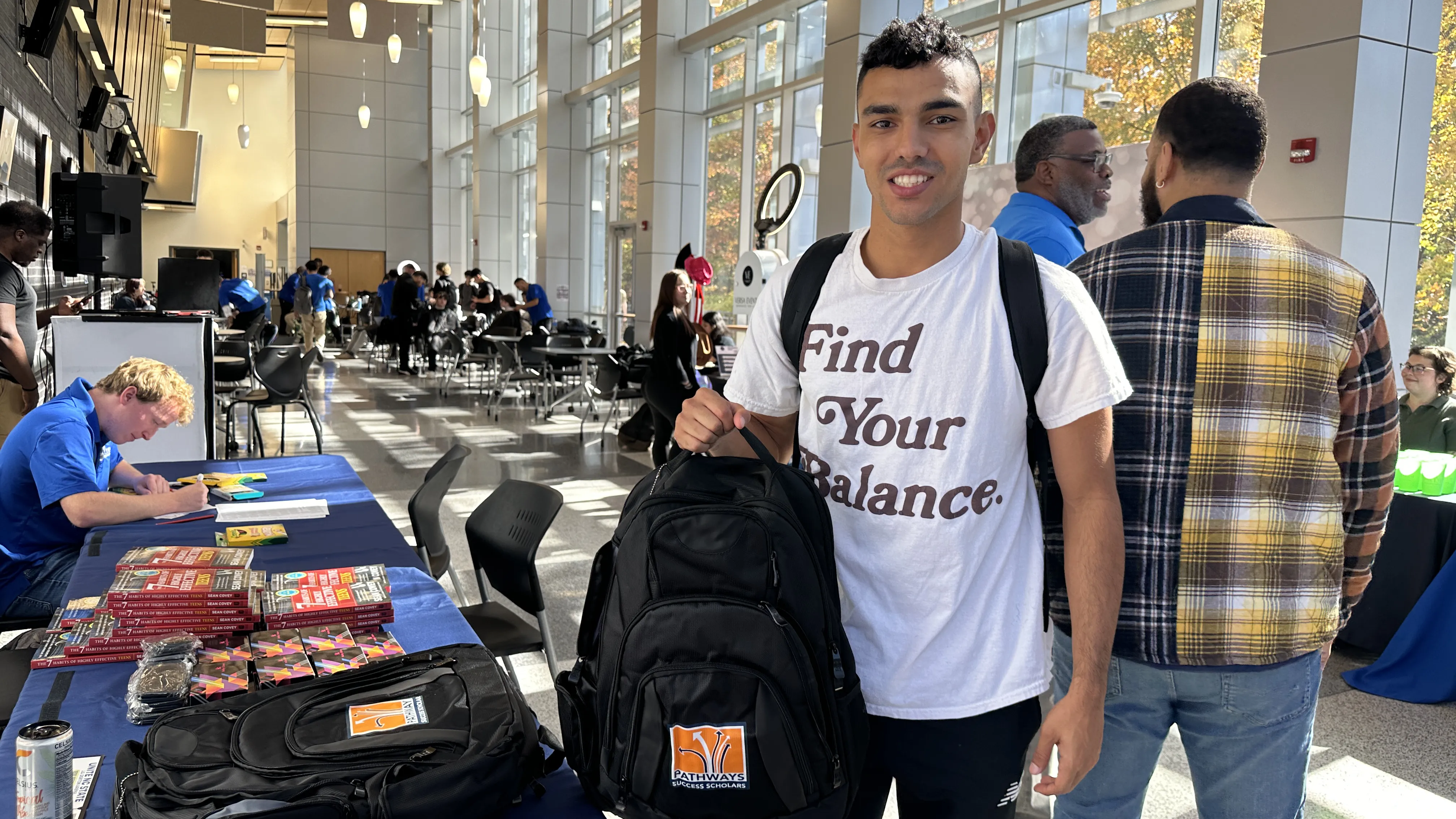 A first-generation college student shows off his backpack.