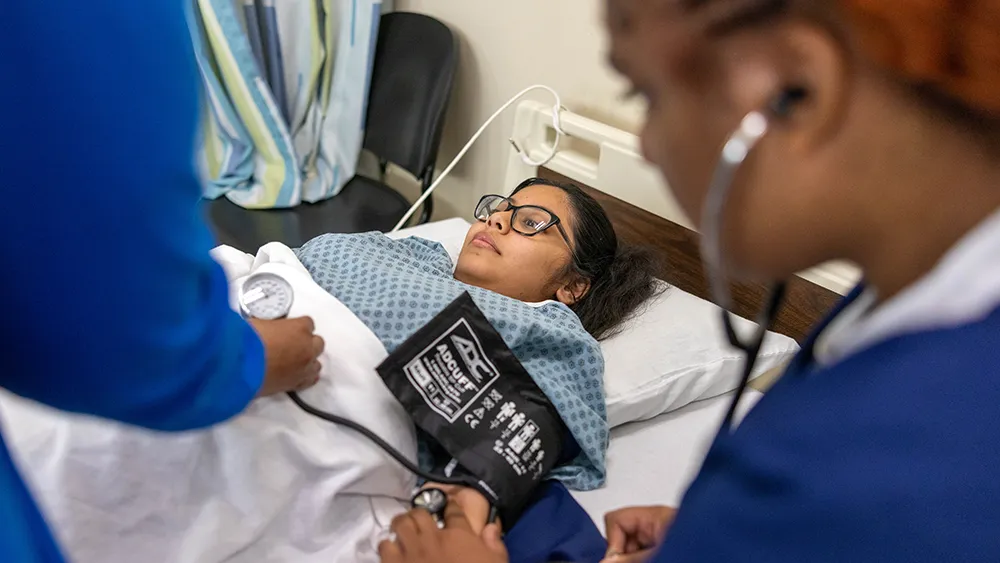 A Nurse Aide student takes a patient's blood pressure.