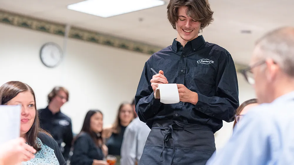 A waiter takes a lunch order from two people.