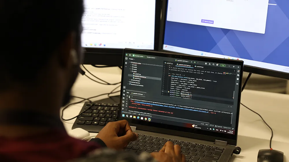 A student works on computer code on his laptop computer.