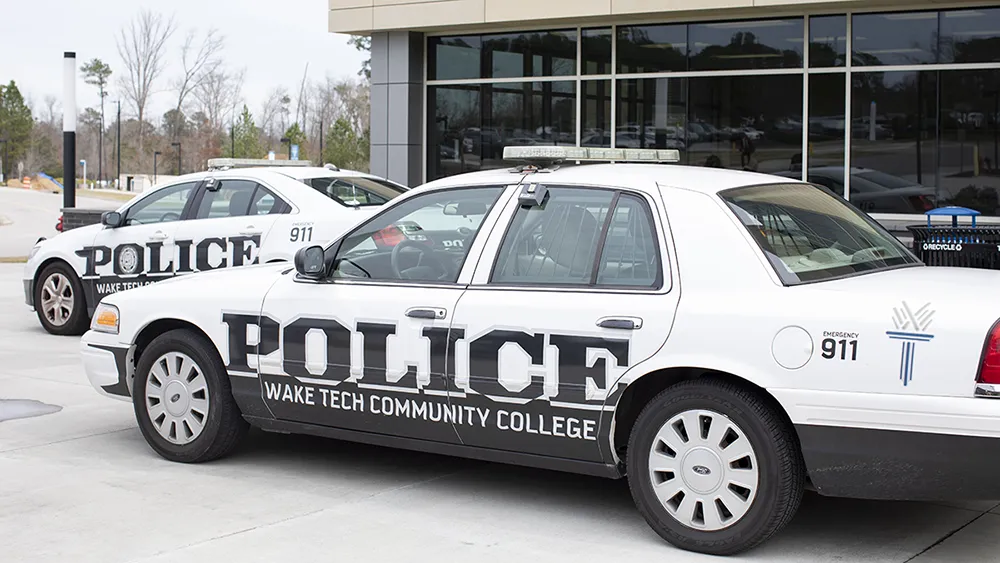 Two Wake Tech College Police cars parked next to a building
