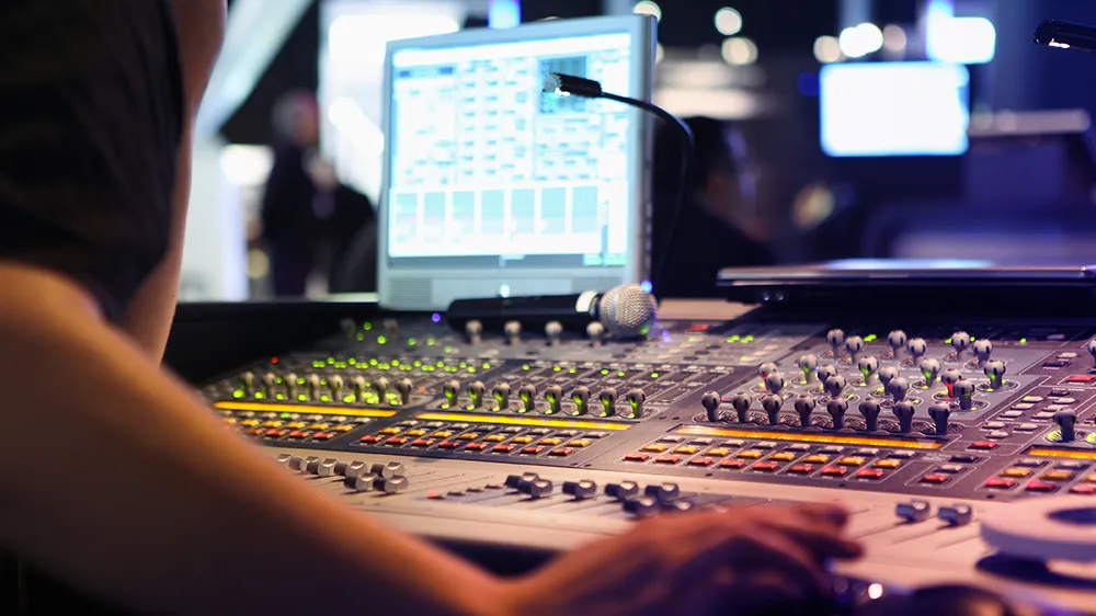 An engineer sits at the control panel at a radio station.