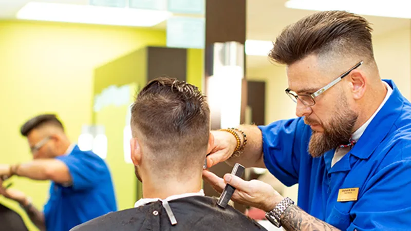 A student in Wake Tech's non-degree Barbering School cuts a man's hair.