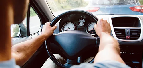 A man holds the steering wheel while driving a vehicle
