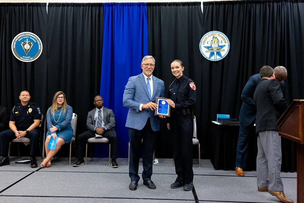 Wake Tech President Dr. Scott Ralls poses for a photo with a member of the latest class to graduate from Wake Tech's Basic Law Enforcement Training Academy.