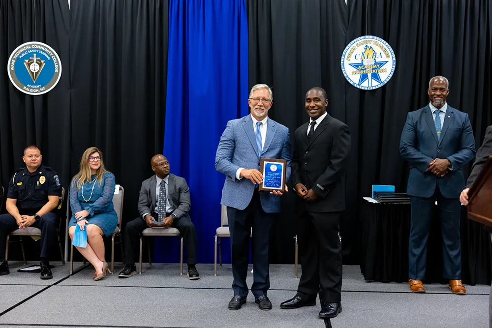 Wake Tech President Dr. Scott Ralls poses for a photo with a member of the latest class to graduate from Wake Tech's Basic Law Enforcement Training Academy.