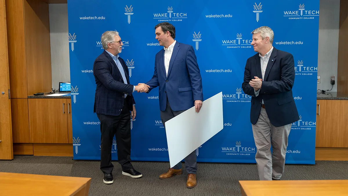 Wake Tech President Dr. Scott Ralls, left, shakes hands with Duke Energy North Carolina President Kendal Bowman as Matt Smith, Wake Tech vice president of Development and Strategic Partnerships, looks on.