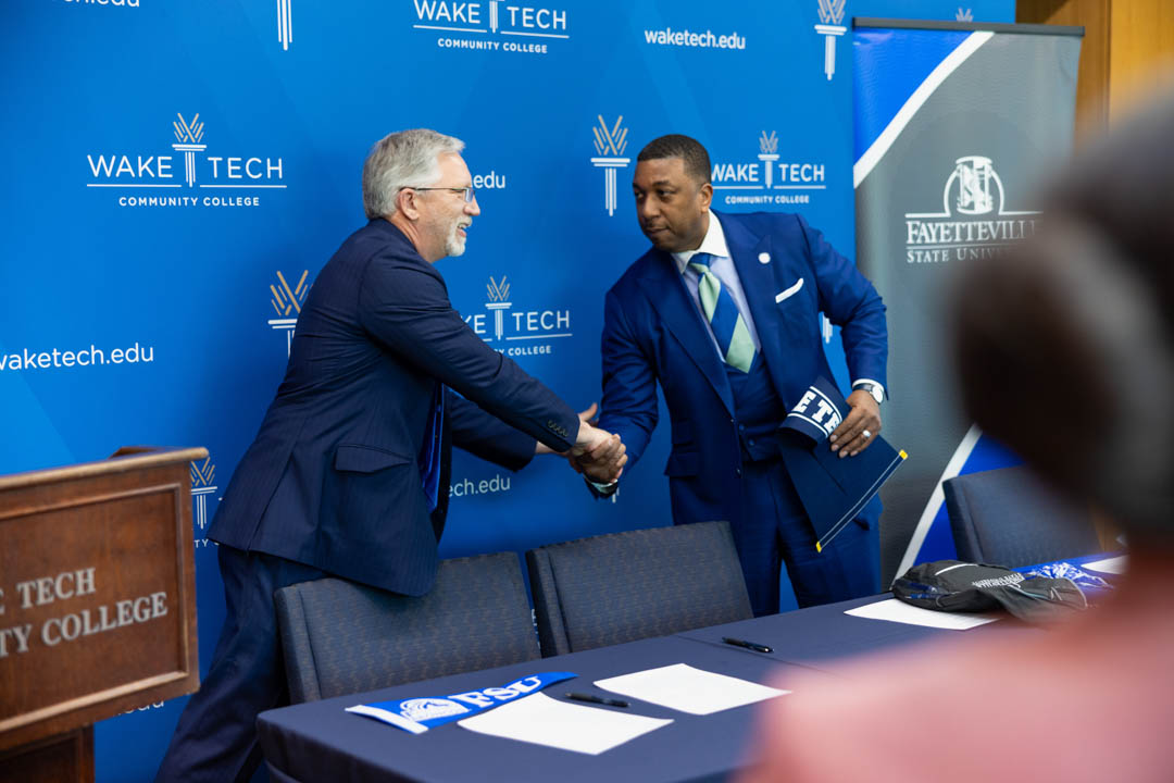 Wake Tech President Dr. Scott Ralls, left, and Fayetteville State University Chancellor Darrell Allison shake hands after signing a transfer agreement.