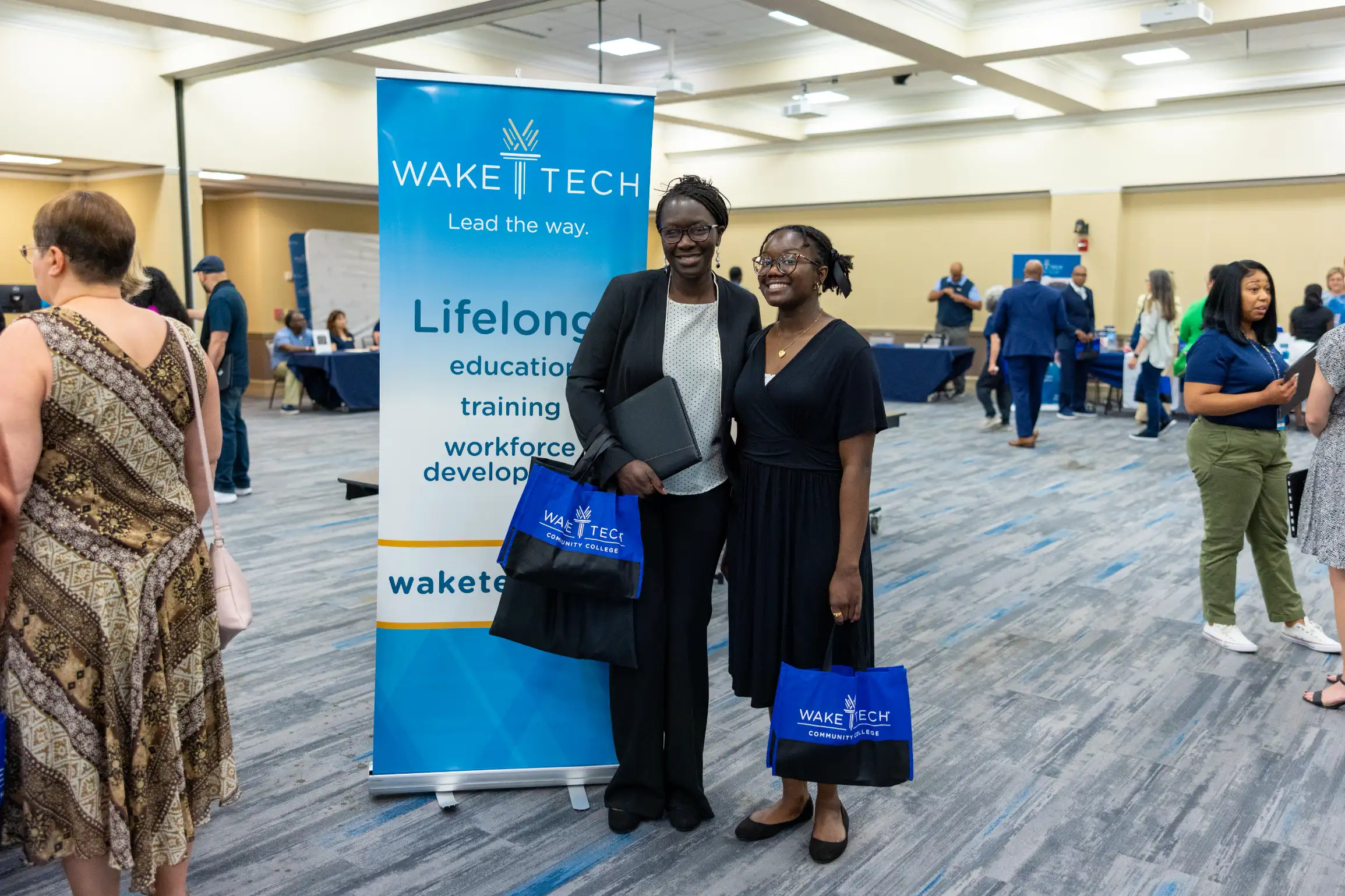 Two job seekers pose next to a sign promoting Wake Tech's Job Fair.