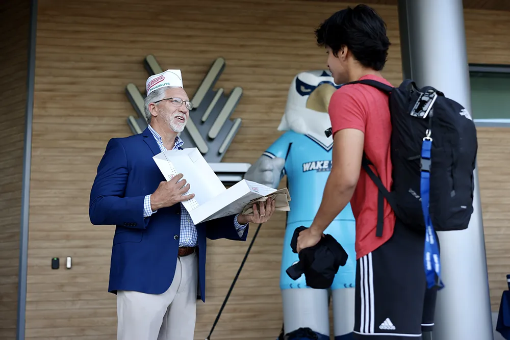 Wake Tech President Dr. Scott Ralls hands out donuts to students on the first day of the 2024-25 academic year.