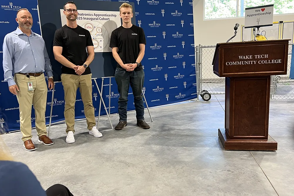 Two Wake Tech students who will serve as biomechatronics apprentices at Fulifilm Biotechnologies pose for a photo during a ceremony marking the launch of the apprenticeship program.