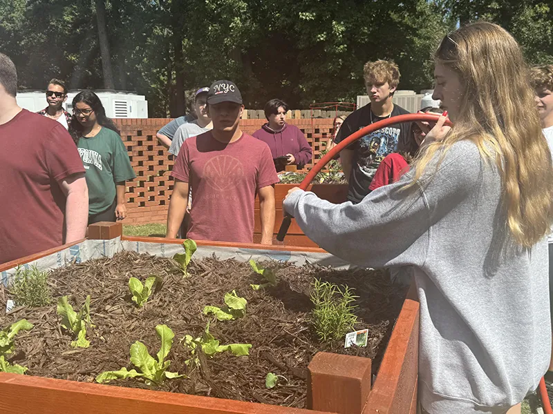 A Wake Tech student waters the vegetable garden on Southern Wake Campus.