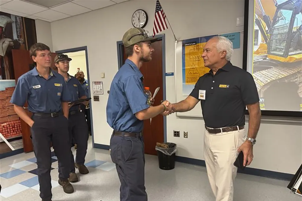 Gregory Poole III shakes the hand of one of the first Wake Tech students to graduate from an apprenticeship program with his company.