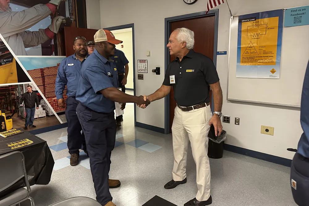 Gregory Poole III shakes the hand of one of the first Wake Tech students to graduate from an apprenticeship program with his company.