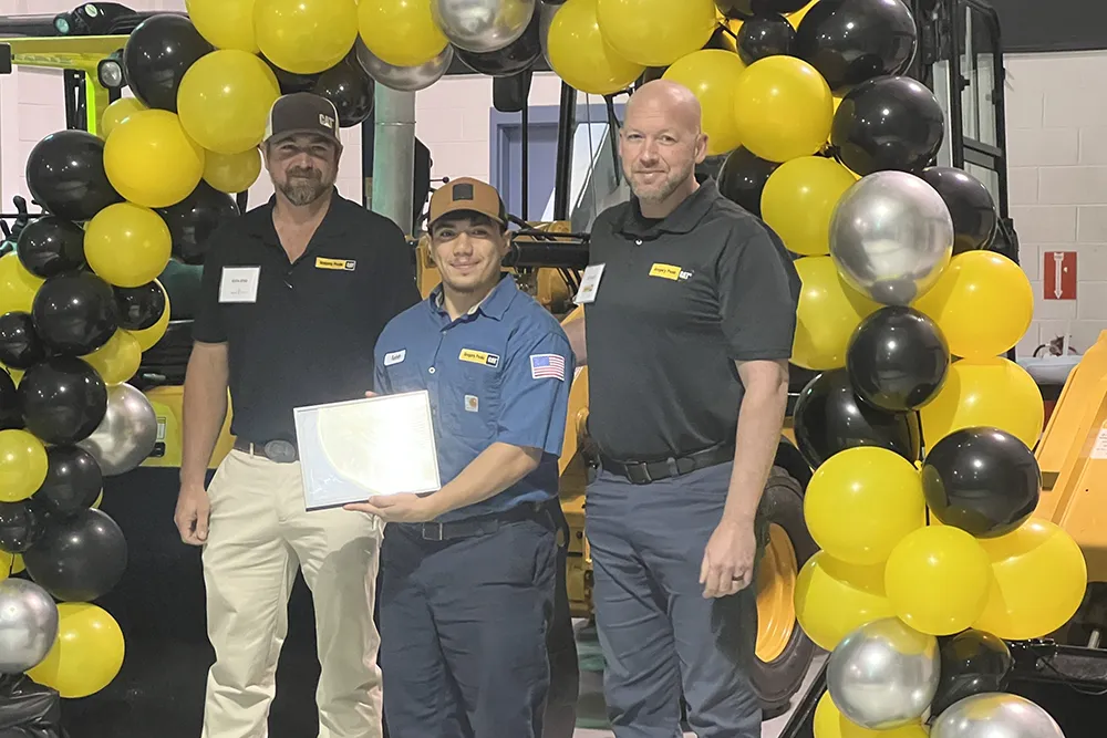 A Wake Tech student poses with instructors in front of a balloon archway after earning a Journeyworker Certificate from the college's apprenticeship program with Gregory Poole Equipment Co.