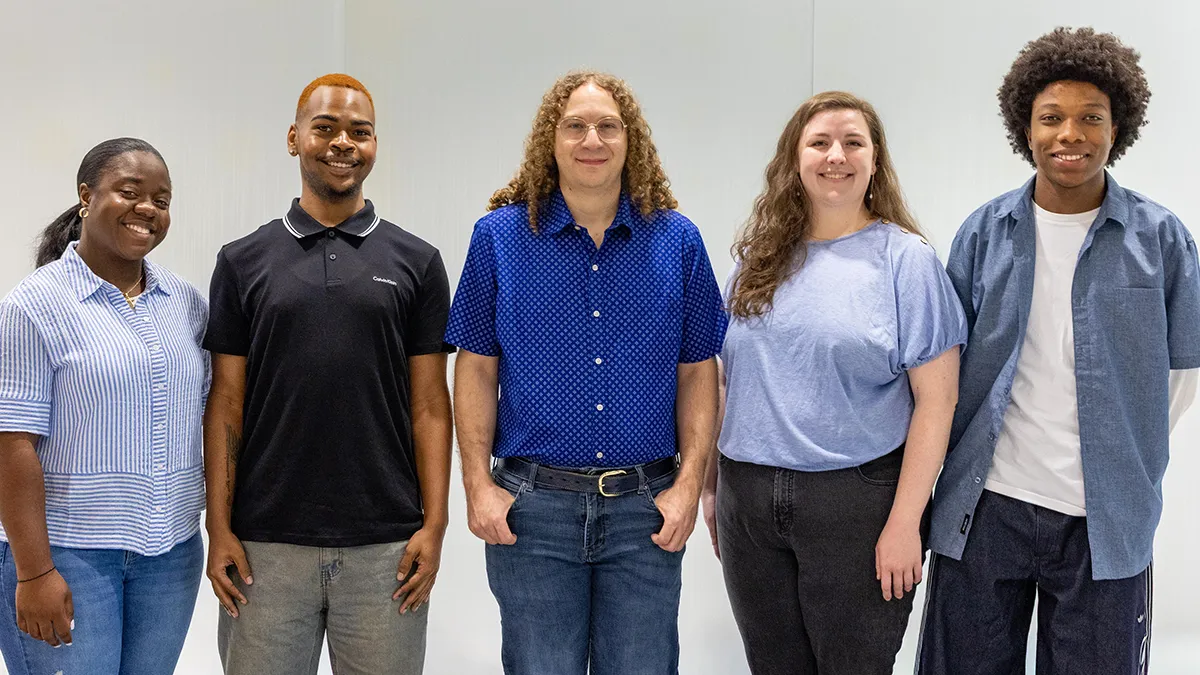 Three men and two women pose for a photo.