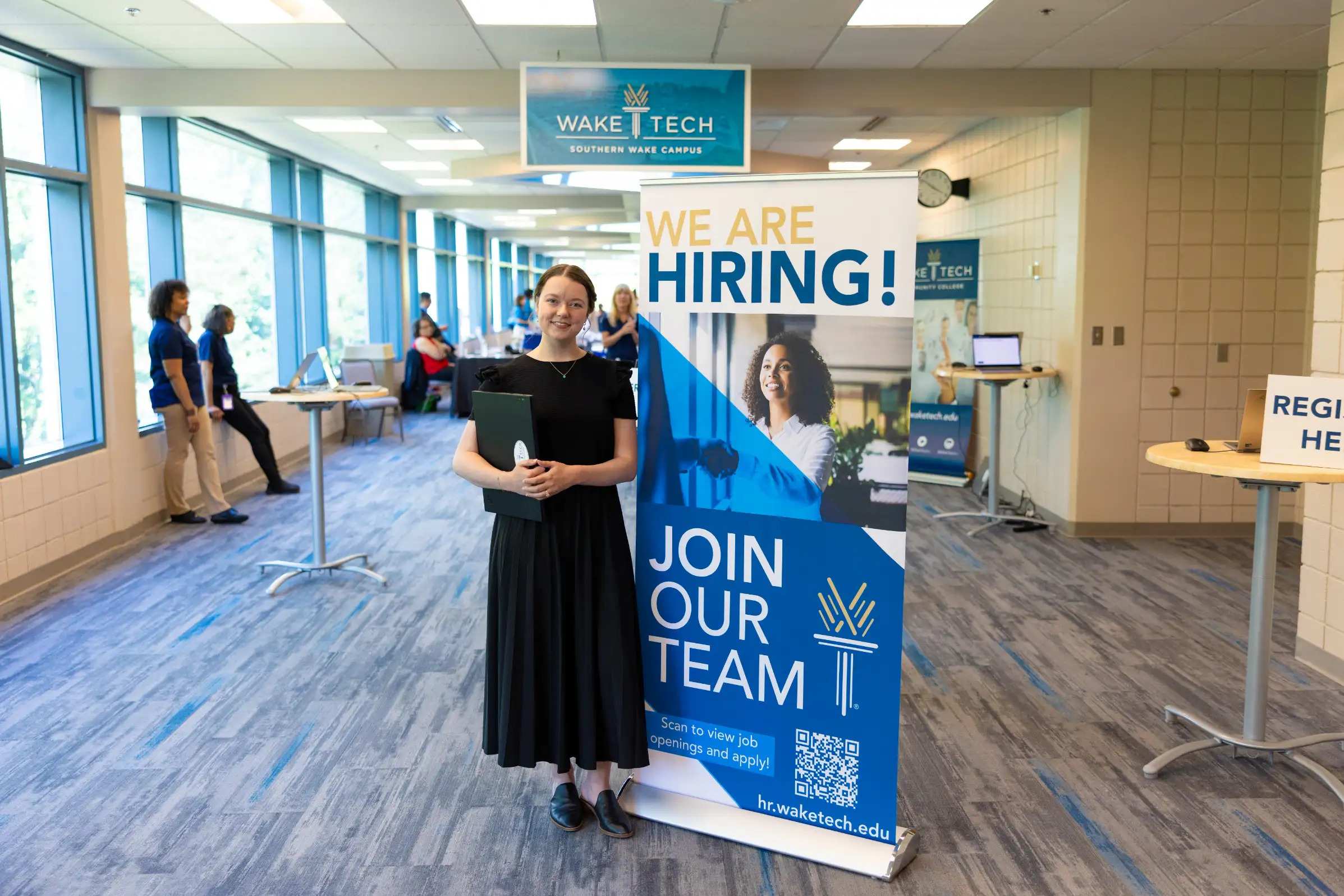 A job seeker poses next to a sign promoting Wake Tech's Job Fair.