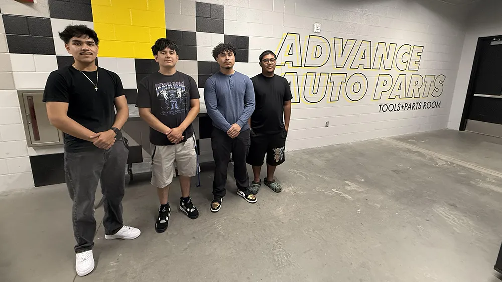 Four future Wake Tech students pose for a photo in front of the Advance Auto Parts logo.