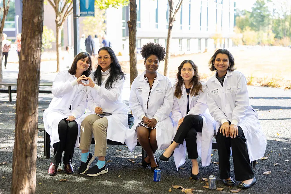 Students sitting on bench with two making heart symbol with hands