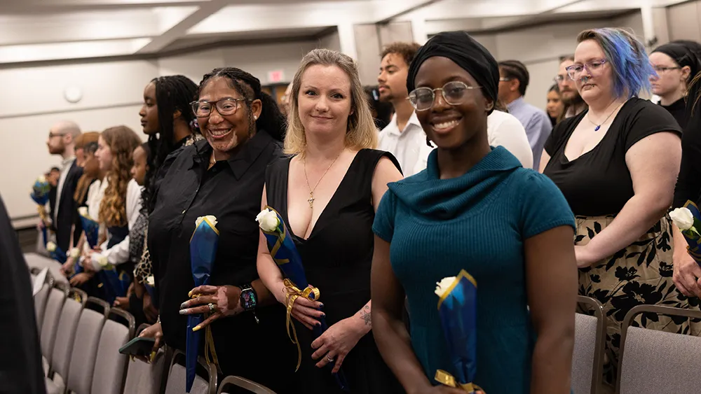 Students hold white roses at Wake Tech's Phi Theta Kappa induction ceremony.