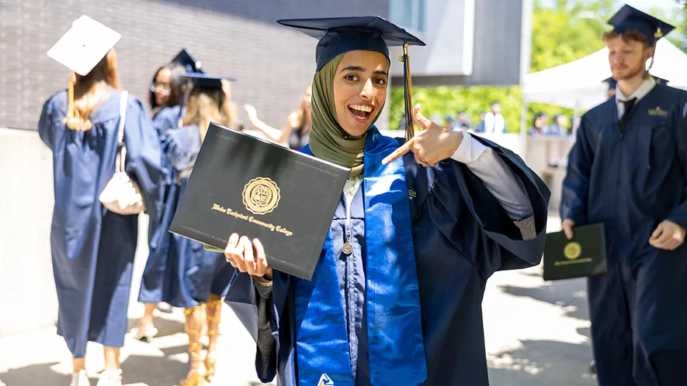A Wake Tech graduate points to her diploma following the commencement ceremony.