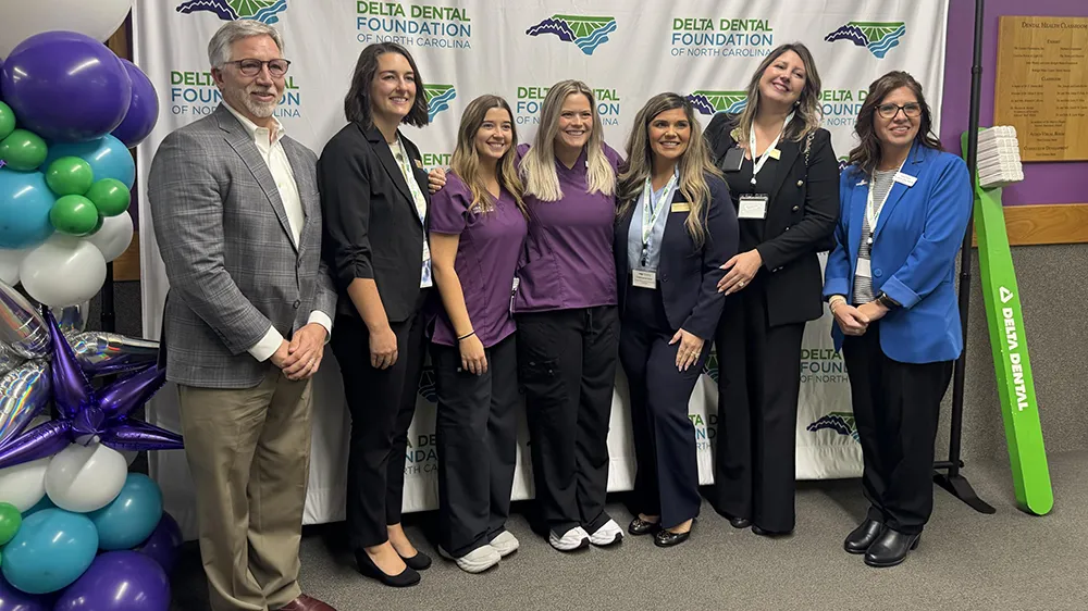 Wake Tech President Dr. Scott Ralls and Health Sciences officials and students pose for a photo amid colorful balloons and a giant green toothbrush.