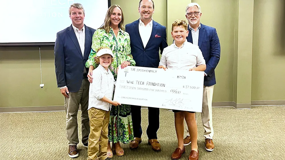 Will Smith and his family pose with Wake Tech Foundation Director Matt Smith, left, and Wake Tech President Dr. Scott Ralls, right, after announcing an endowed scholarship the family created.