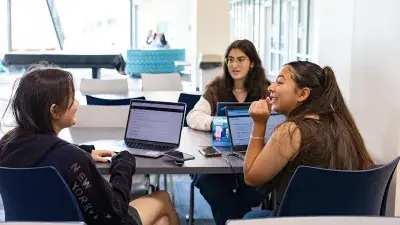 Three Wake Tech students gather at a table.