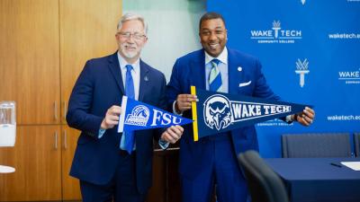 Wake Tech President Dr. Scott Ralls, left, and Fayetteville State University Chancellor Darrell Allison shake hands after signing a transfer agreement.