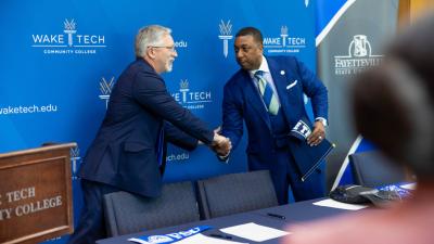 Wake Tech President Dr. Scott Ralls, left, and Fayetteville State University Chancellor Darrell Allison shake hands after signing a transfer agreement.