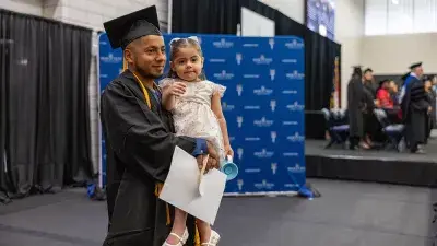Two graduates in caps and gowns take a selfie after their Wake Tech commencement ceremony.