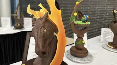 Two men in white chef coats stand next to woman with a medal around his neck holding a certificate.