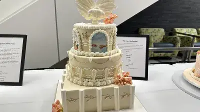 Two men in white chef coats stand next to woman with a medal around his neck holding a certificate.