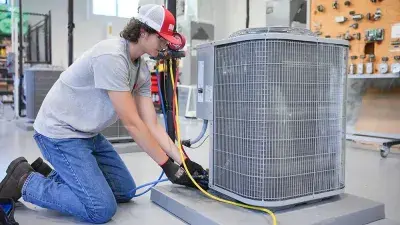 A male student works on a air conditioning unit in a Wake Tech lab.