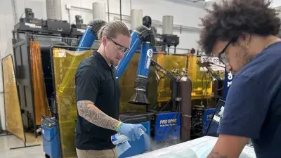 Technicians prepare glass to be installed in an automobile.