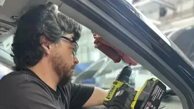 Technicians prepare glass to be installed in an automobile.