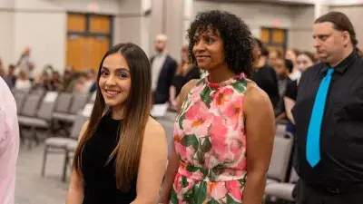 A female Wake Tech student smiles as she processes in at the start of the Phi Theta Kappa honor society induction ceremony.
