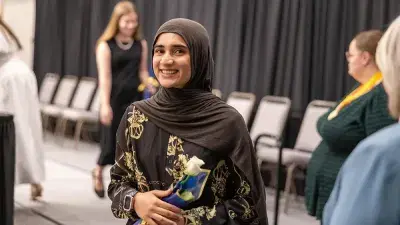 A female Wake Tech student smiles as she processes in at the start of the Phi Theta Kappa honor society induction ceremony.